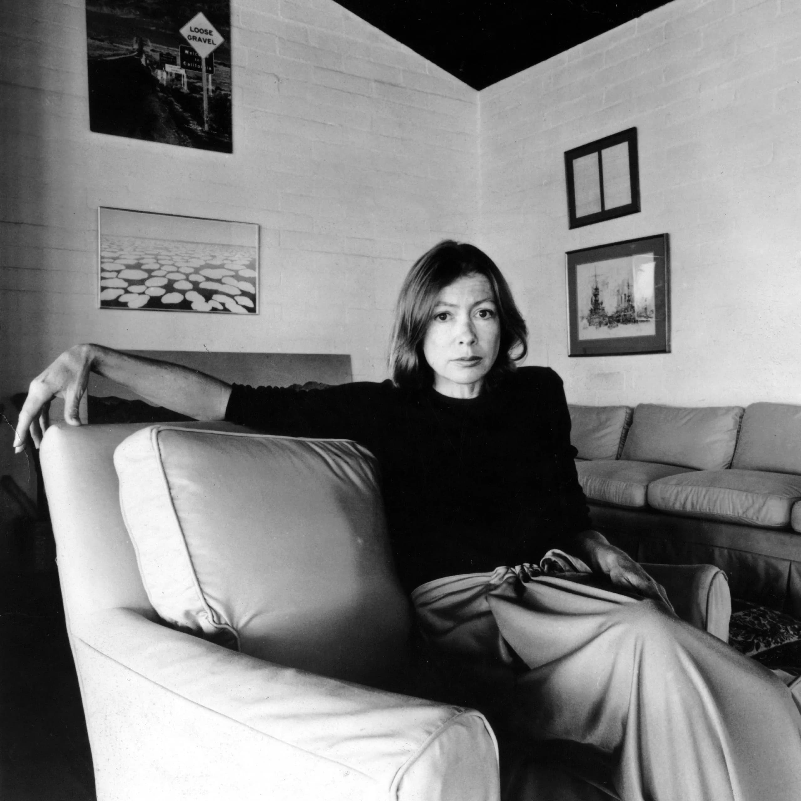 Black-and-white editorial portrait of Joan Didion seated in an armchair.